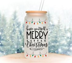 a white mason jar with merry little christmas lettering on it and a straw in the lid