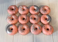 twelve donuts with frosting and sprinkles arranged on a wooden surface