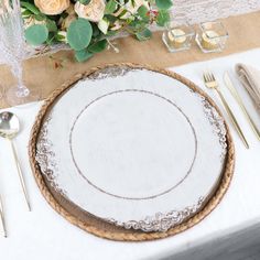 an empty plate on a table with silverware and flowers