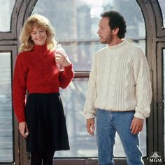 a man and woman standing next to each other in front of a large window with arched windows