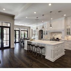 a large kitchen with white cabinets and wooden floors