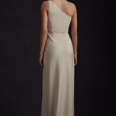 the back of a woman in a long dress with one shoulder and an asymmetrical neckline