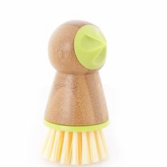 a small wooden brush with yellow bristles on it's head and a green top