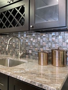 a kitchen with marble counter tops and stainless steel appliances on the wall, along with black cabinets