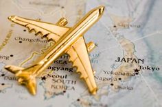 a gold airplane brooch sitting on top of a map with japan in the background