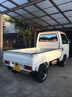 a white pick up truck parked in a carport area next to a tree and building