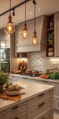 a kitchen filled with lots of counter top space and lights hanging from the ceiling above it