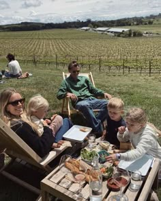 a group of people sitting around a picnic table in the middle of an open field