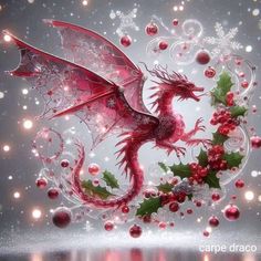 a red dragon sitting on top of a table next to christmas balls and holly berries