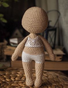 a crocheted doll sitting on top of a woven table cloth next to a potted plant