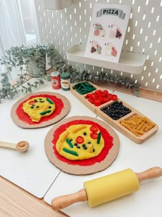 three pizzas with different toppings on them sitting on top of a table next to a rolling pin