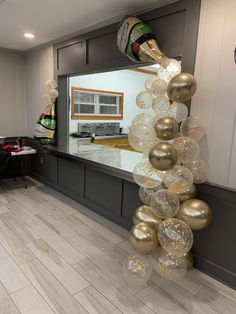 balloons and streamers are hanging from the ceiling in front of a counter with chairs