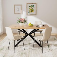 a dining room table with chairs and fruit on the table in front of two framed pictures