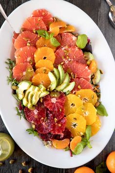 a white plate topped with oranges, avocado and grapefruit slices