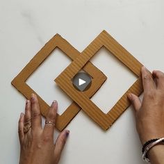 two hands are working on an object made out of cardboard