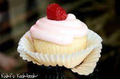 a cupcake with white frosting and raspberries on top