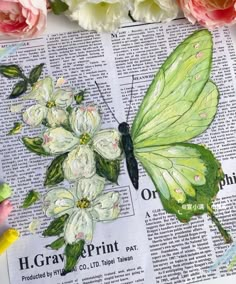 a green butterfly sitting on top of an open book next to pink flowers and peonies