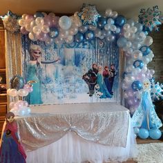 a frozen princess themed party with balloons and streamers on the wall, including an ice queen table