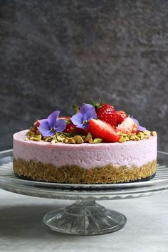 a cake with strawberries and blue flowers on top is sitting on a glass plate