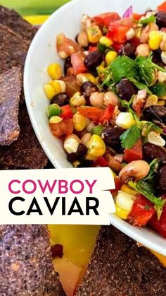 a bowl filled with corn, black beans and cilantro next to tortilla chips