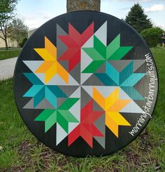 a large circular sign with many different colored stars on it's side in the grass