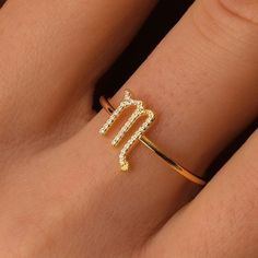 a close up of a person's hand wearing a gold ring with the letter m on it