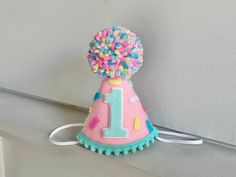 a pink birthday hat with colorful pom poms