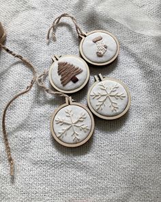 three snowflake ornaments are hanging from twine on a white fabric covered surface