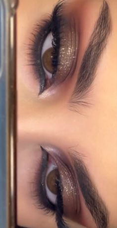 a woman's eye with long lashes and brown eyeshadow is reflected in a mirror