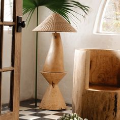 a table lamp sitting on top of a checkered floor next to a potted plant