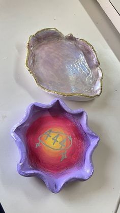 two purple bowls sitting next to each other on a white counter top with gold trim