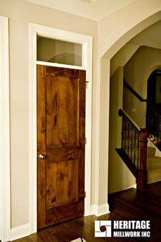 a wooden door in the middle of a room with hardwood floors and white painted walls