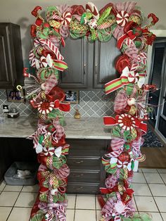 a christmas wreath made out of candy canes and bows on a kitchen counter top