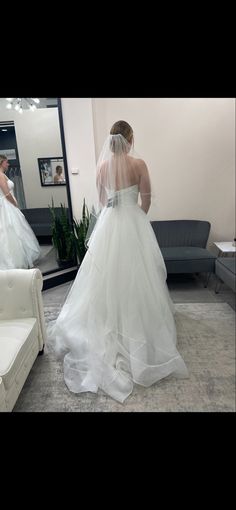 a woman in a wedding dress looking at herself in the mirror