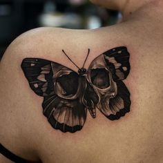 a black and white butterfly tattoo on the back of a woman's left shoulder