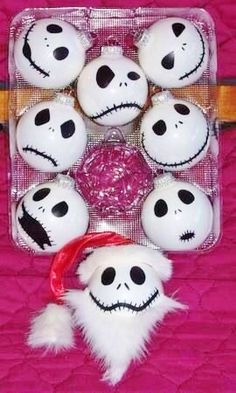 a bunch of white balls with black faces on them in a plastic container next to a red ribbon