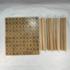 wooden letters and numbers are laid out on a sheet of paper next to some sticks