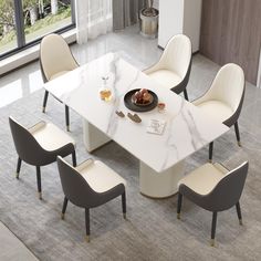 a white marble dining table with four chairs around it and a bowl of fruit on top