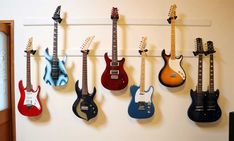 several guitars are hanging up on the wall