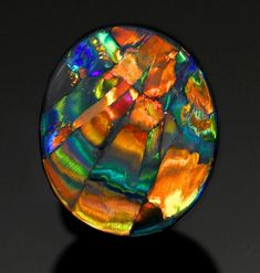 an oval shaped multicolored glass object on a black surface