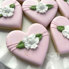 heart shaped cookies decorated with white flowers and green leaves on a platter for valentine's day