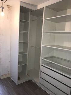 an empty room with white shelving and wood flooring in the middle of it