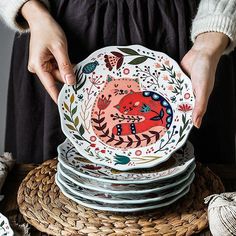 a woman holding a stack of plates in her hands