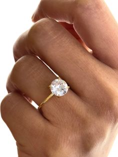 a woman's hand with a gold ring and a white topazte stone