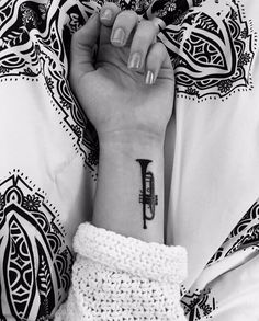 a woman's wrist with a musical instrument tattoo on it