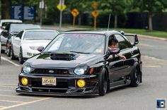 a black car driving down a street next to other cars