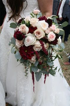 a bride holding a bouquet of red and white flowers