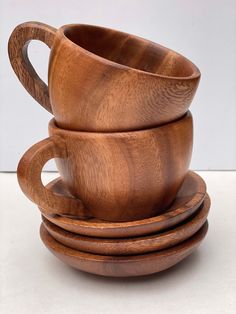 three wooden cups and saucers stacked on top of each other with one cup in the middle