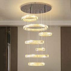 a modern chandelier hanging from the ceiling in a room with beige walls and flooring