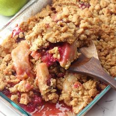 an apple crisp in a glass dish with a wooden spoon